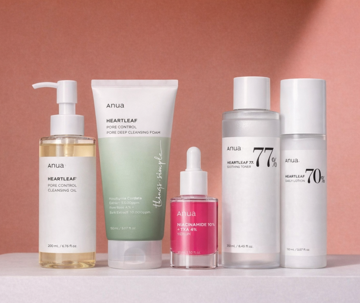 Set of Anua skincare products with visible brand names on a pink background