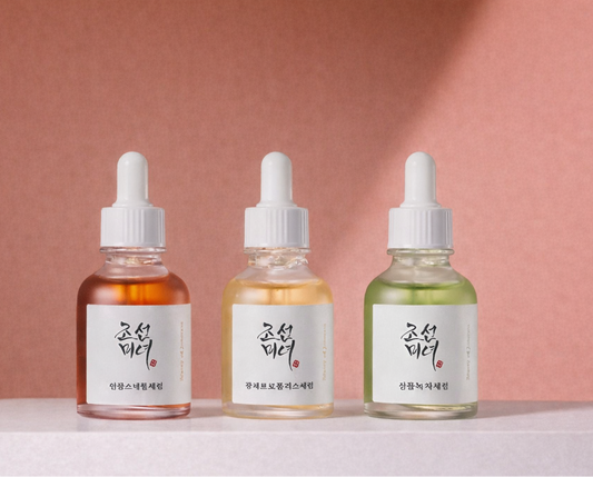 Three Beauty of Joseon skincare serum bottles with droppers on a pink background